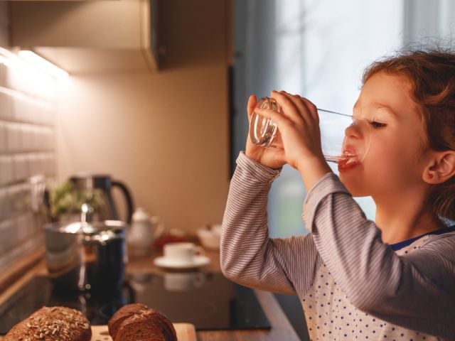 Girl drinking a glass of water in the kitchen