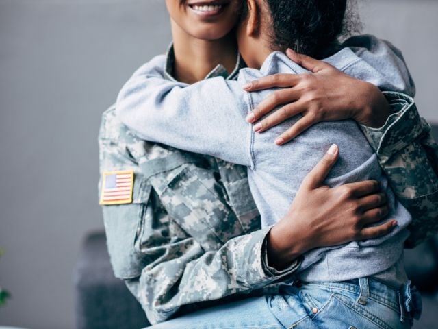 Child hugging parent in military fatigues 