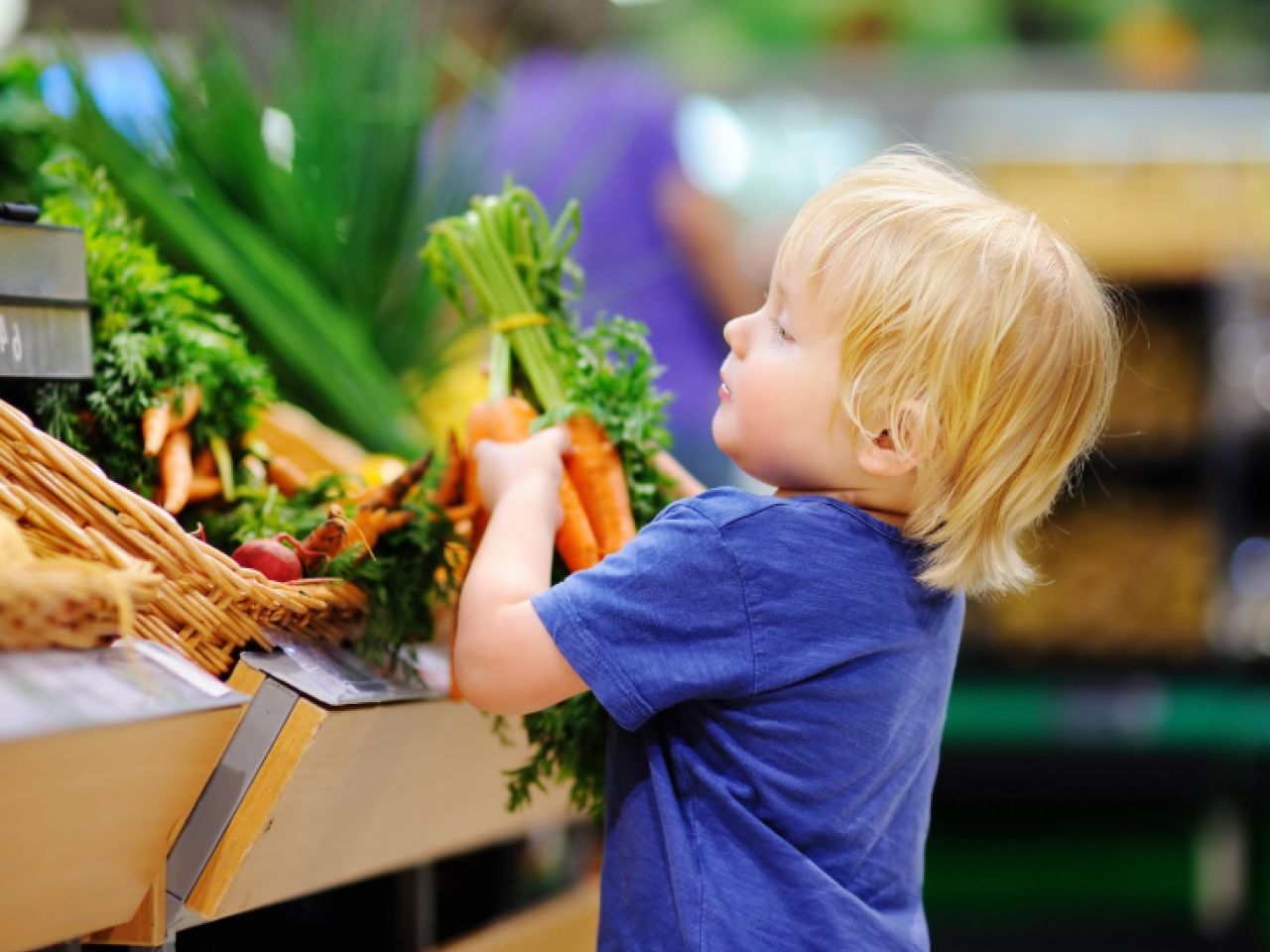 Boy grabbing carrots at the supermarket